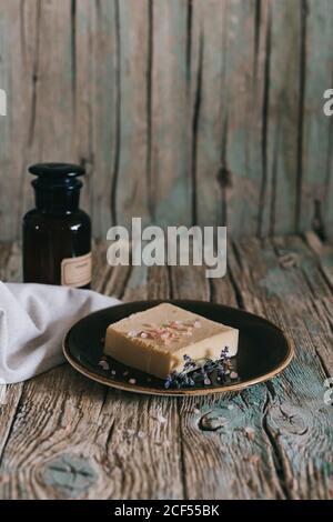 Pieces of organic soap placed on napkins near bottle of natural oil on weathered timber table Stock Photo