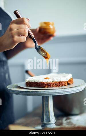 House wife wearing apron making finishing touches on birthday dessert chocolate cake.Woman making homemade cake with easy recipe,sprinkling powdered s Stock Photo