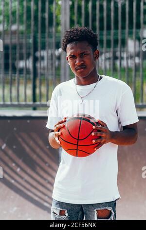Cheerful African American player holding orange ball and looking at camera with wide smile Stock Photo