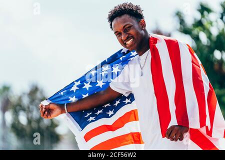 Serious African American man holding American flag on shoulder and looking away Stock Photo