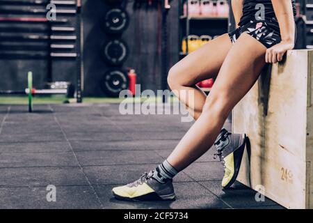 Crop tired female in sportswear relaxing in gym on blurred background Stock Photo