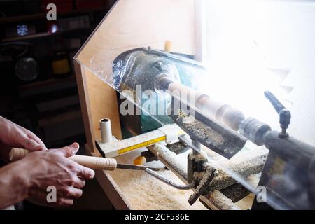 man's hands hold chisel near lathe, man working at small wood lathe, an artisan carves a piece of wood using a manual lathe Stock Photo
