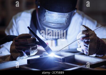 Male in face mask welds with argon-arc welding Stock Photo
