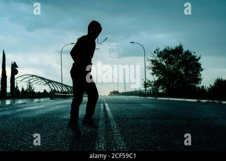 faceless person in casual wear walking on city road with sky and nature on background
