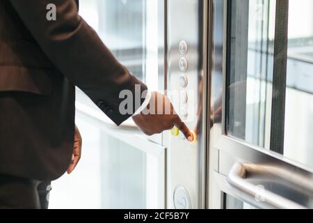 finger presses the elevator button. Red button. sunset light. businessman is a lift. high floor. hand reaches for the button of the elevator call. Stock Photo