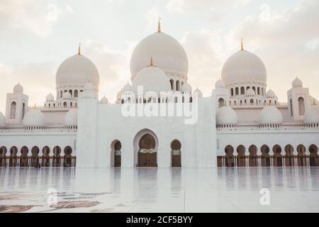 Beautiful white mosque with domes and minarets under bright blue sky, Dubai Stock Photo