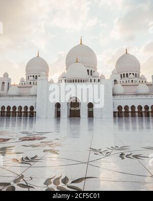 Beautiful white mosque with domes and minarets under bright blue sky, Dubai Stock Photo