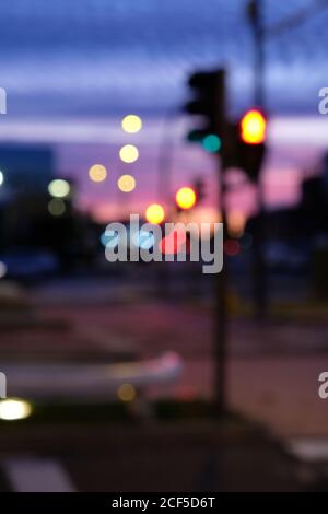 Defocused glowing lights of stoplight located on crossroad in city during majestic sunset Stock Photo