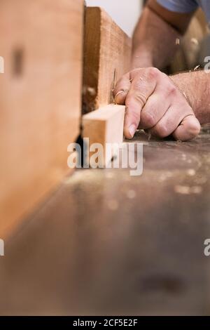 Low angle of closeup unrecognizable carpentry master milling timber using modern electric machine in light contemporary workshop Stock Photo