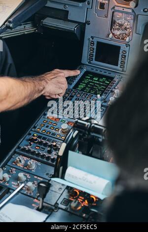 Crop anonymous male pilot using keyboard of flight management system in ...