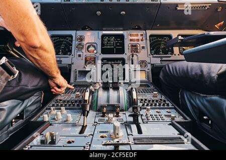 Crop anonymous male pilot using keyboard of flight management system in ...