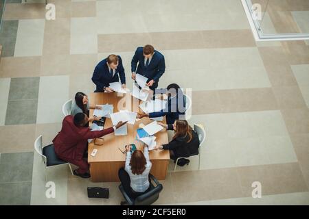 Office workers gather around a table to do research and implement new ideas. High angle view of multi-ethnic business people discussing in board room Stock Photo