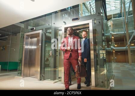 business group comes out from glass Elevator Stock Photo