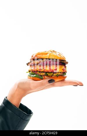 Crop palm of faceless Woman holding delicious burger with two patties isolated on white background Stock Photo