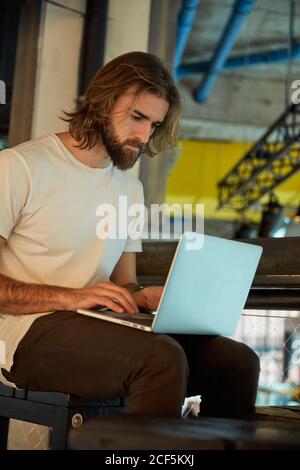 Young bearded handsome man sitting and working holding notebook on laps Stock Photo