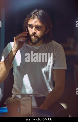 Young bearded handsome man in cafe behind window talking on phone Stock Photo