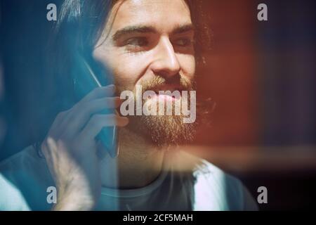 Young bearded handsome man in cafe behind window talking on phone Stock Photo