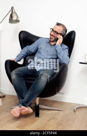 man talking smiling on the phone from the sofa at home Stock Photo