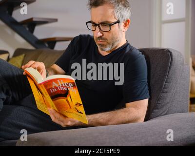 man reading a relaxed book alone on the sofa in the living room at home Stock Photo
