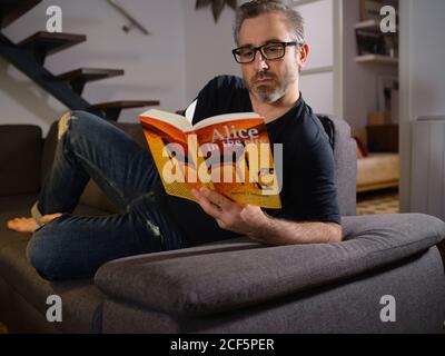 man reading a relaxed book alone on the sofa in the living room at home Stock Photo