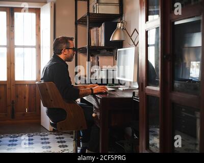 man working at home desk with computer via internet Stock Photo