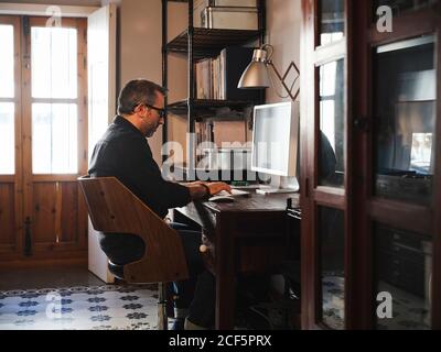 man working at home desk with computer via internet Stock Photo