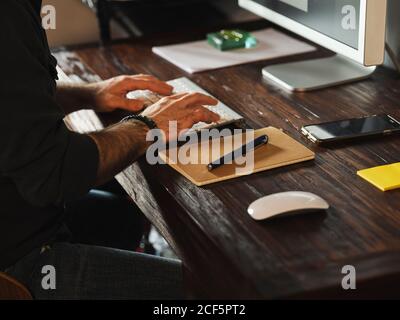 detail of man hands working at home desk with computer via internet typing on computer Stock Photo