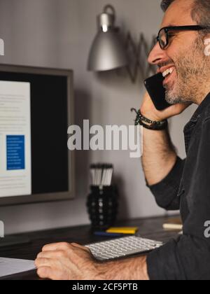 man working at home desk with computer over the internet talking on the phone Stock Photo
