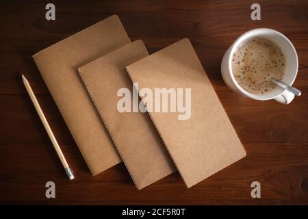 cool traditional notebooks on wooden table and pencil and mug with coffee Stock Photo