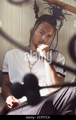 Handsome man sitting on stairs while looking away Stock Photo - Alamy