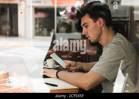 Male freelancer using laptop and smartphone in cafeteria Stock Photo