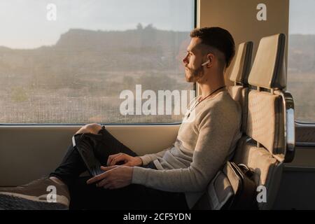 Concentrated male passenger using laptop in train Stock Photo