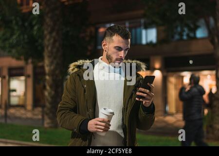 Serious young man using smartphone in street Stock Photo