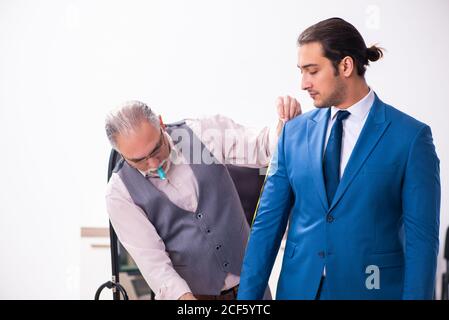 Young businessman visiting old tailor Stock Photo