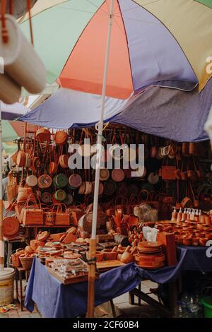 Market tent with wicker handbags and pottery placed on counter under parasol in Bali Stock Photo
