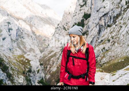 Active Woman hiker in red jacket with heavy backpack walking in mountain in peaks of Europe, Asturias, Spain Stock Photo