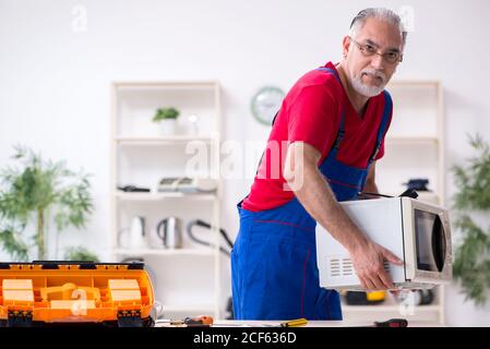 Old repairman repairing appliances in his workshop Stock Photo