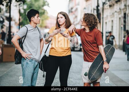 Multiethnic people in casual clothes talking while standing along urban street Stock Photo