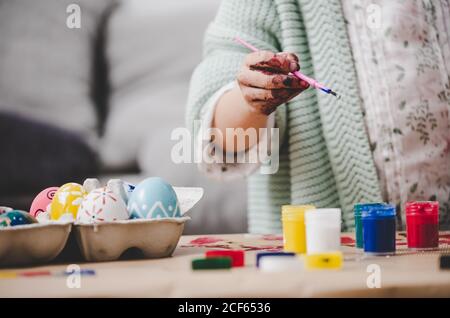 Child with brush coloring chicken eggs at table Stock Photo