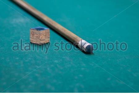A cue stick and chalk on a pool table Stock Photo