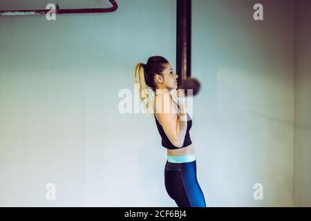 Young Woman doing pull ups in gym Stock Photo