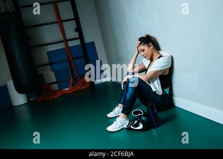 SportsWoman in boxing gloves sitting in gym Stock Photo