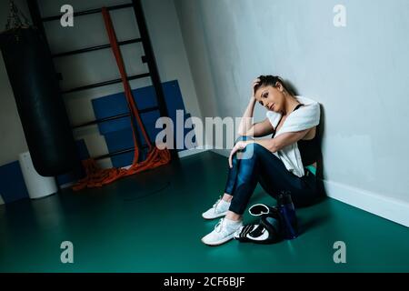 SportsWoman in boxing gloves sitting in gym Stock Photo