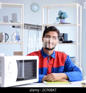 The young repairman fixing and repairing microwave oven Stock Photo