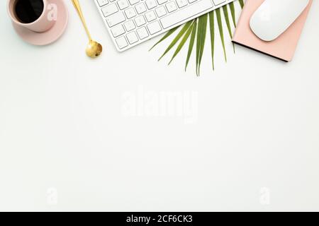 Top view of creative workspace with netbook and mug of hot espresso placed on palm leaf Stock Photo