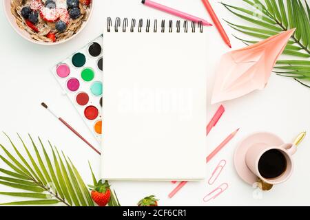 Top view of blank notebook and stationery placed on white background with tasty breakfast bowl and cup of espresso Stock Photo