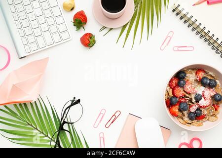Top view of office table with modern keyboard and mouse placed near breakfast bowl and cup of espresso Stock Photo
