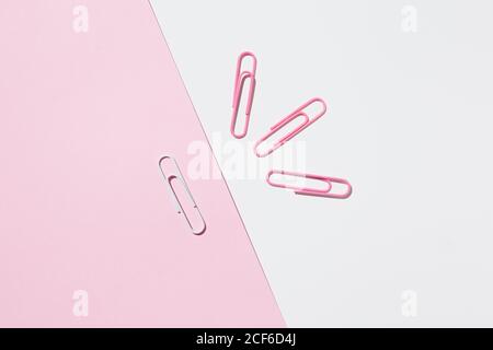 Top view of white and pink paper clips arranged on colorful background showing concept of uniqueness Stock Photo
