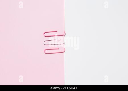 Top view of white and pink paper clips arranged on colorful background showing concept of uniqueness Stock Photo