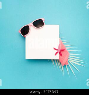 Top view composition with sunglasses and colorful starfish arranged near blank paper sheet copy paste on blue background Stock Photo